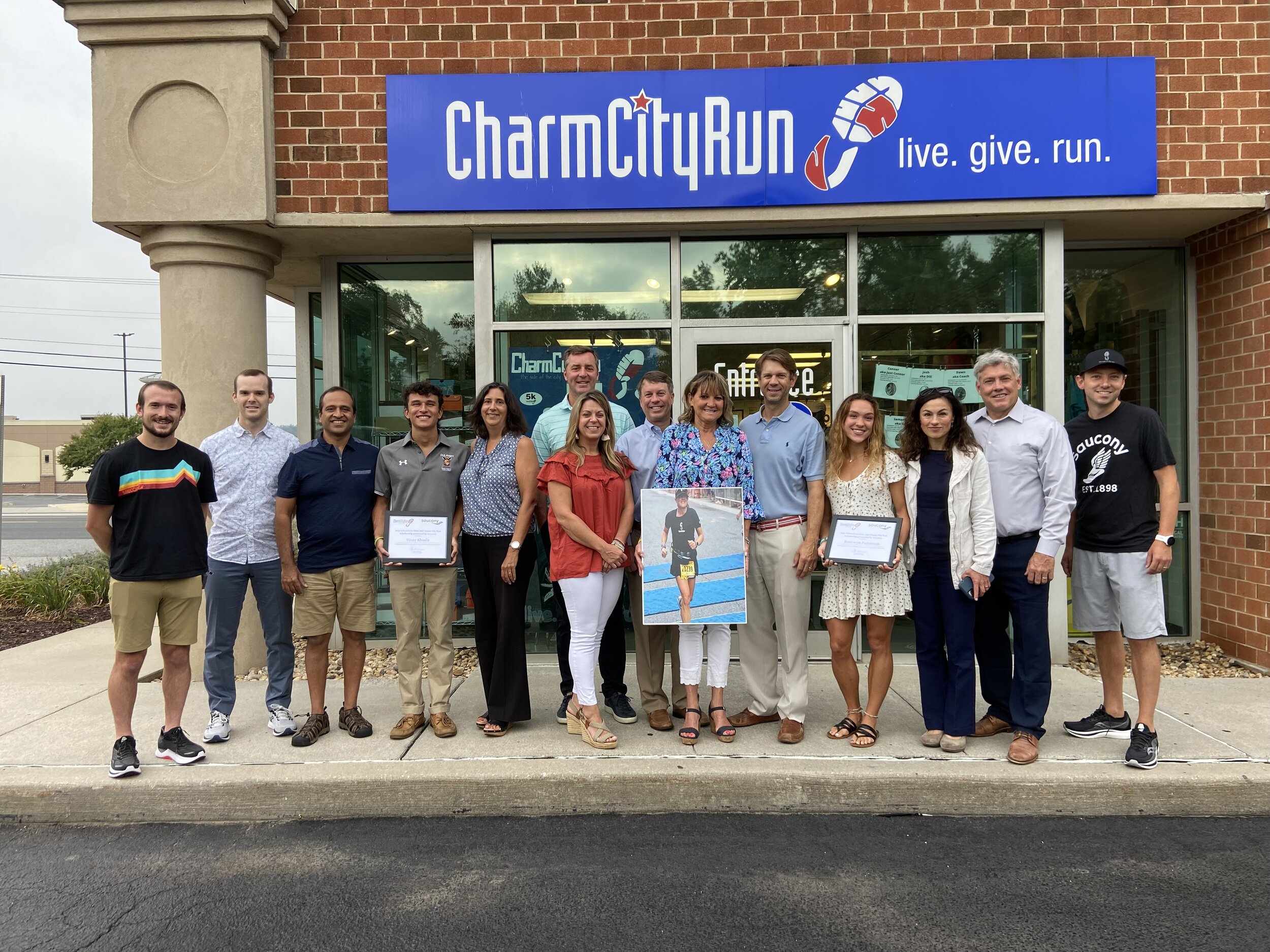 2021 Scholarship Winners Vinay Khosla and Bronwyn Patterson alongside their families, Amy Amy Schuerholtz Metz’s family, Saucony representatives Zach Opdenaker and Ken Holmes, and Charm City Run COO Tom Mansfield